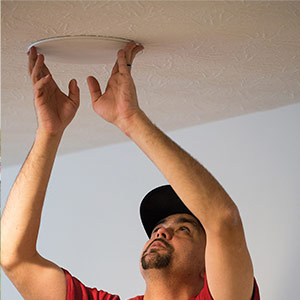 A Parts Express employee installing a ceiling speaker for testing and demonstration purposes.