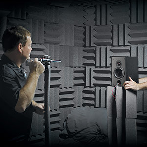 Two Parts Express employees using a diagnostic tool to test a speaker in a room covered with sound dampening material.