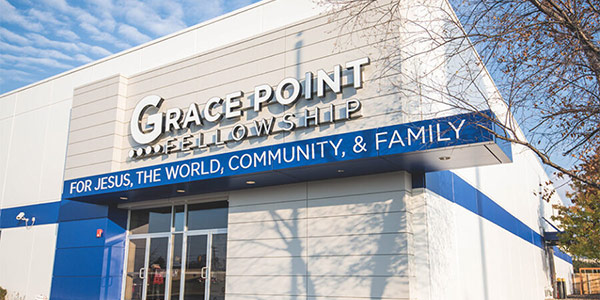 A white and blue building. The signage above the doorway reads: Gracepoint Fellowship. For Jesus, The World, Community, & Family.